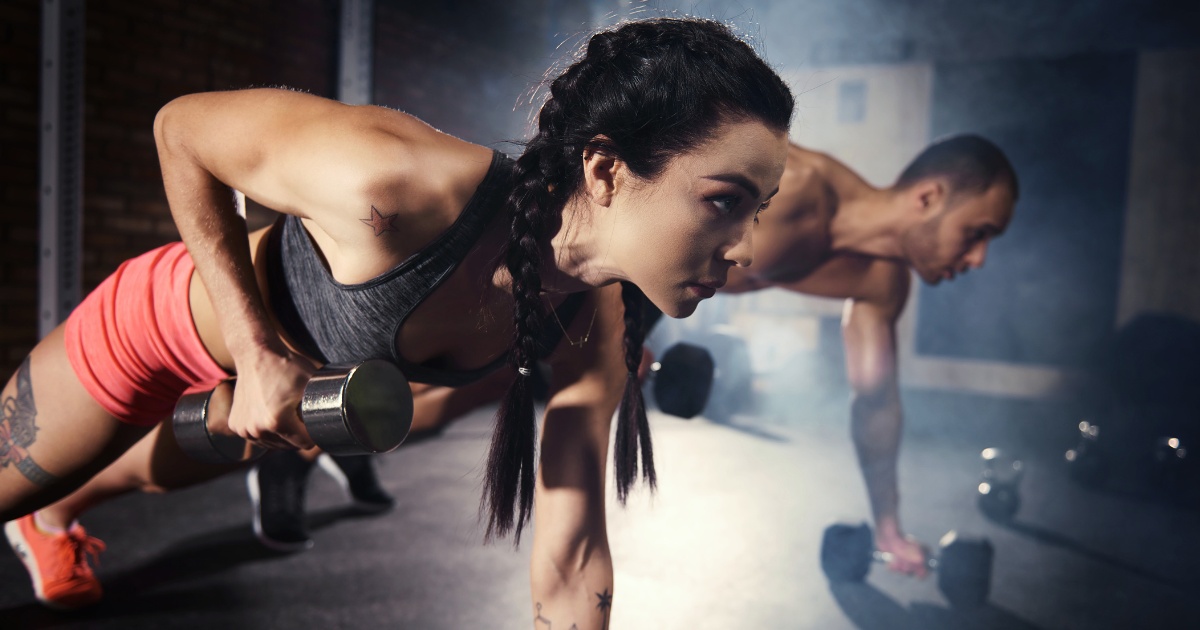 A woman and a man doing push-ups with weights