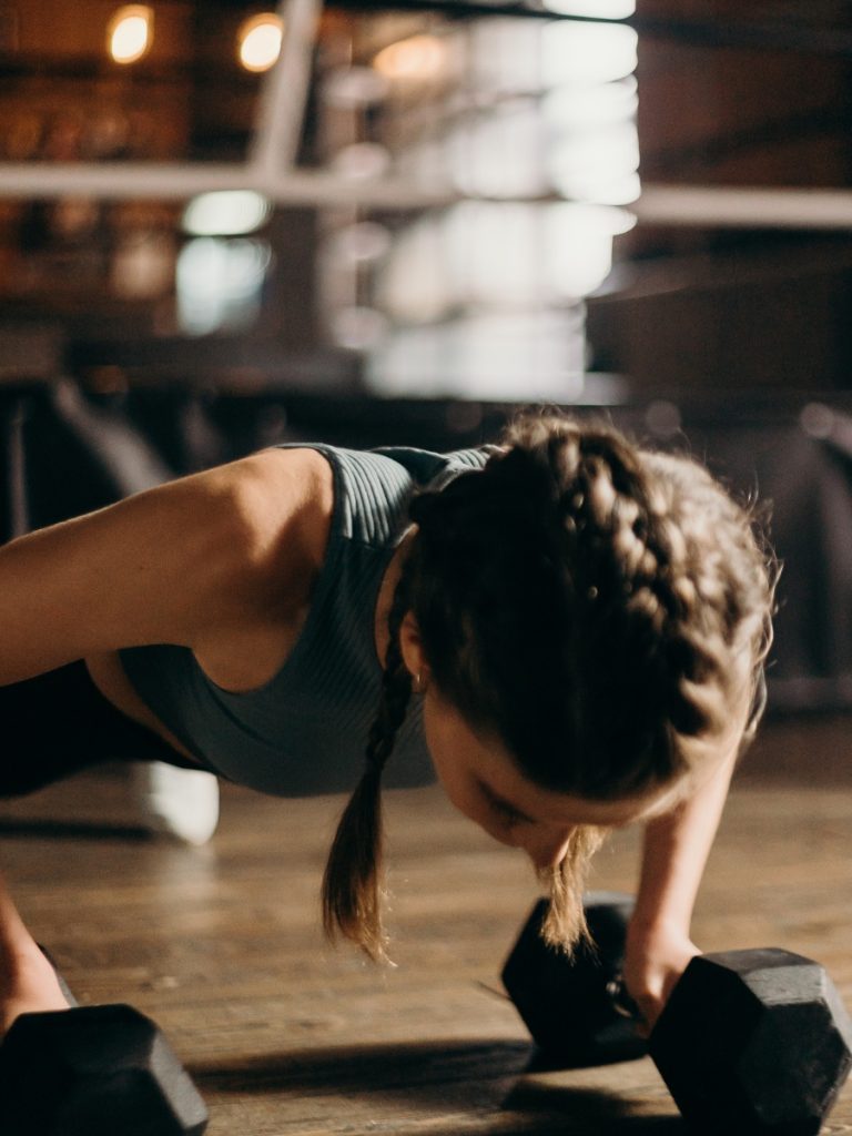 Woman with a braid doing push-ups with weights