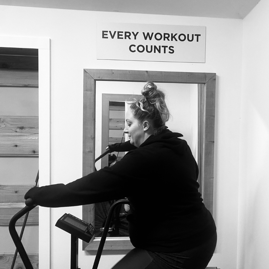 Black and white photo of a woman working out on an exercise machine.